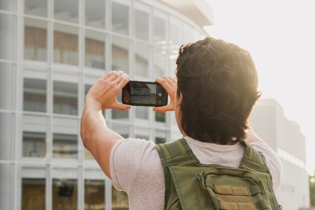 Man taking photo of building, rear view