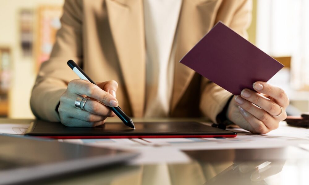 Close up of woman holding passport and working in tablet