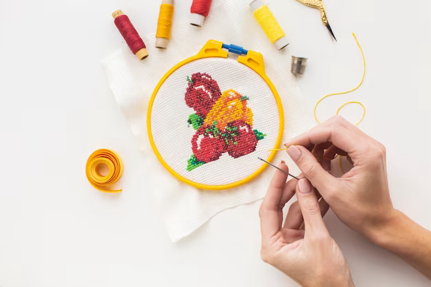 Hands embroider a cross stitch pattern